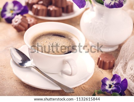 Postcard with cup of cooffee, chocolate candies in flower shape and pansy. Holiday food concept. Retro style toned.