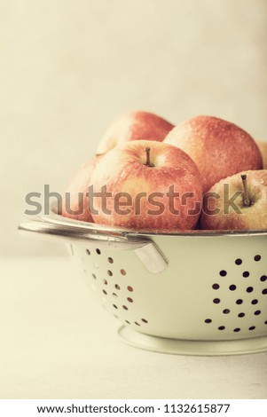 Fresh red apples in green metal strainer on light background. Healthy food concept with copy space. Retro style toned.
