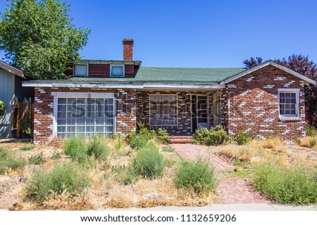Abandoned Brick Home With Overgrown Front Yard Royalty-Free Stock Photo #1132659206