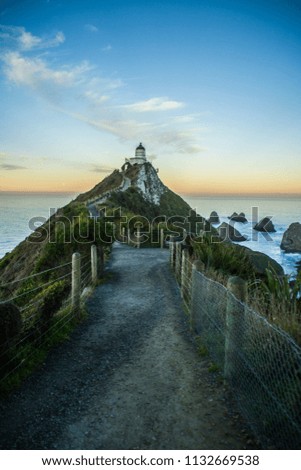 Travel New Zealand. Beautiful scenic view of the Nugget Point Lighthouse while colorful sunset. Favourite tourist attraction at Southland, South Island.