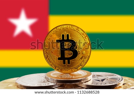 Bitcoin BTC on stack of cryptocurrencies with Togo flag in background. The cryptocurrency coin is golden and in focus