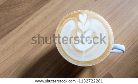 A white cup of hot latte art coffee  in coffee shop