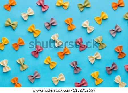 Italian pasta pattern on a blue background. Various colors of bow tie farfalle pasta viewed from above. Top view. Repetition. Full frame Royalty-Free Stock Photo #1132732559