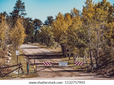 Campground closed sign on gate on unpaved road at autumn sunny day in Colorado, USA. 