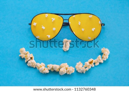 Popcorn and glasses in the form of a smile, on a blue background. abstract image. Pastime of the concept