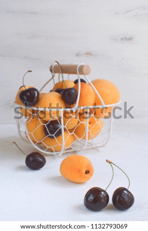 Apricots and cherries in metal basket Summer fruit and berries concept Harvesting Organic fruits White background Copy space