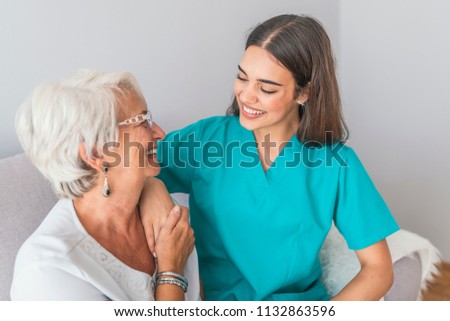 Nurse Talking With Senior Woman Sitting In Chair On Home Visit. Female Community Nurse Visits Senior Woman At Home. Female Support Worker Visits Senior Woman 