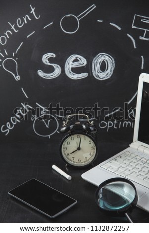 SEO Search engine optimization concept Magnifying glass, clock, smartphone on a black background with an inscription chalk SEO