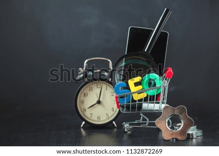 SEO Search engine optimization concept Colored letters of SEO with clock, magnifying , smartphone, gears in a basket on a black background Copy space
