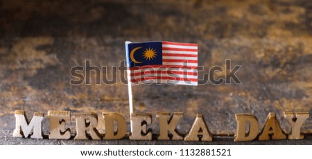 Malaysian flag with MERDEKA (or Independence) DAY text on wooden board.