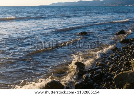 rocky sea shore with pebble beach, waves with foam
