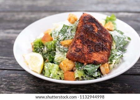 Blackened salmon Caesar salad with parmesan cheese and croutons, on a weathered wood table Royalty-Free Stock Photo #1132944998