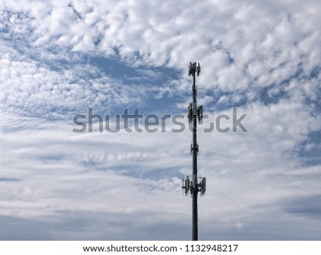 Cell Phone Tower with White Clouds - Photograph of cell phone tower against a blue sky with white clouds.  Selective focus on the tower. 