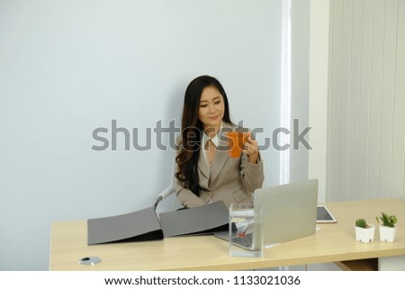 A businesswoman holds a brown coffee mug and prepares information for the meeting.