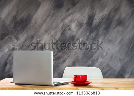 The workplace is equipped with a laptop computer, office equipment, a coffee set and a coffee cup at the office with a wall of decayed mortar.