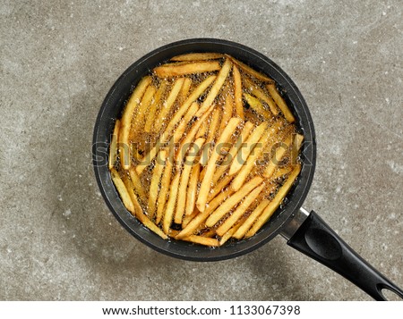 frying french fries in a pan with oil, top view Royalty-Free Stock Photo #1133067398