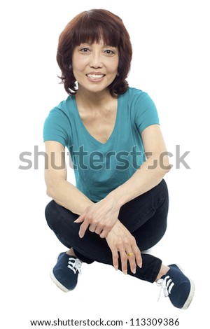 Casual teen girl sitting on the floor isolated against white background
