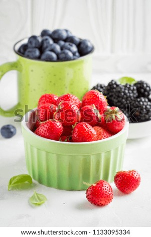 Fresh blueberries, strawberries, blackberries in cups, juicy summer berry on a light background, home harvest, garden