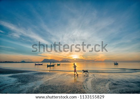 Man and dog running on beach at sunset