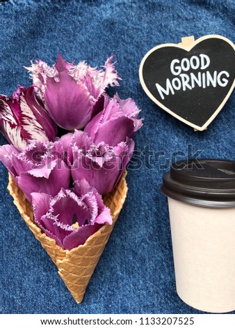 concept spring morning coffee to go on jeans background and purple flowers