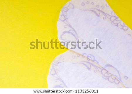 Two daily female pads or sanitary napkin (towel) are on yellow uniform background view from above with clear area of half photo for labels or headers. Female hygienic products for vulvovaginal health