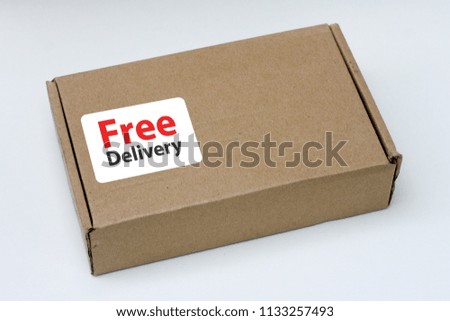 free delivery, business,online shopping, ecommerce and delivery service concept - brown box with note " free delivery " on a gray background