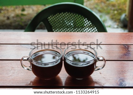 two clear glass cups of tea or coffee on the table. Tea of coffee - difficult choice. Black hot coffee in a glass cup. Low key
