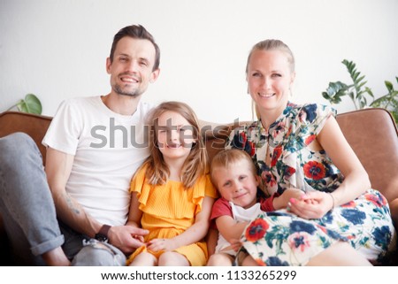Picture of happy parents with their son and daughter sitting on sofa