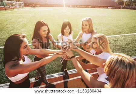 Six women in the stadium putting hands. Group of young sporty people celebrating giving friends a high five, raised hands, gesture of greeting, good-fellowship triumph Royalty-Free Stock Photo #1133280404