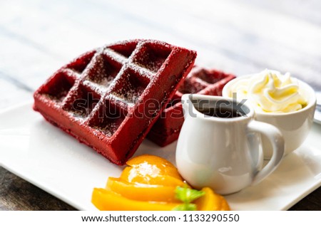 Redvelvet waffle with honey in mini pot and cream and orange color fruit on white plate on old wooden desk near window Royalty-Free Stock Photo #1133290550