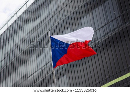 Czech flag waving against windows of modern building