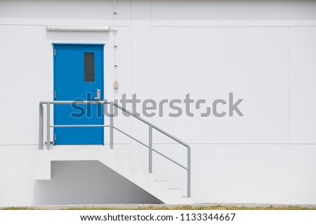 blue steel door with grey metal handrail factory door and fire exit stair.