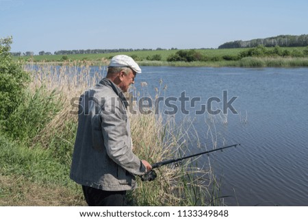 Man fishing while standing on pond bank