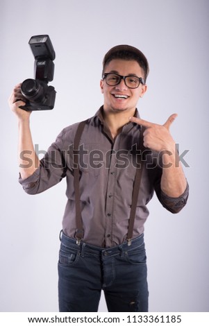 Portrait of a Photographer wearing a classic outfit, pointing his finger at the camera, on his face big smile.