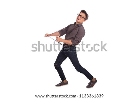 Side shot of a happy young man wearing classic outfit walking and pulling his suspenders, isolated on white background