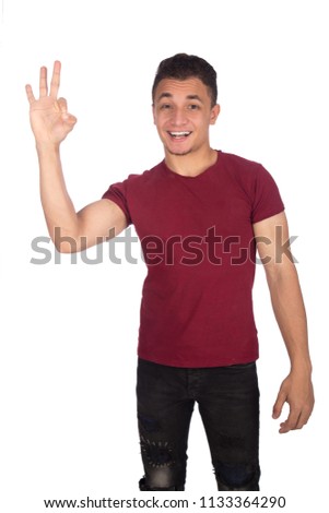 Handsome young man wearing a casual outfit, doing a well-done sign with his right hand and smiling, isolated on white background.