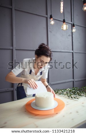 confectioner in a white apron on a dark background with a cupcake