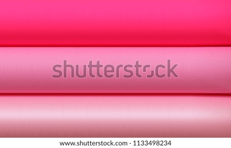 Rolls of paper with different textures and different shades of pink background, photographed from above