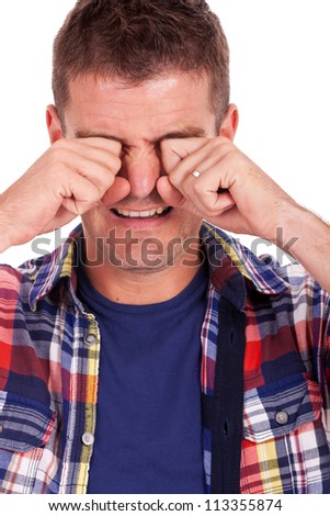 closeup picture of a young casual man crying with his hands covering his eyes. on white background