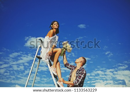 Picture showing man giving flowers and present to woman. Couple in love. Hot babe. Love concept. Sky background. Vacation, travel. Tourism. Love story. Fashion photo. Flowers. Strong man. Love. 
