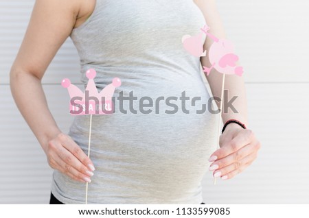 Cropped image of pregnant woman announcement she's having a baby girl using a booth props.