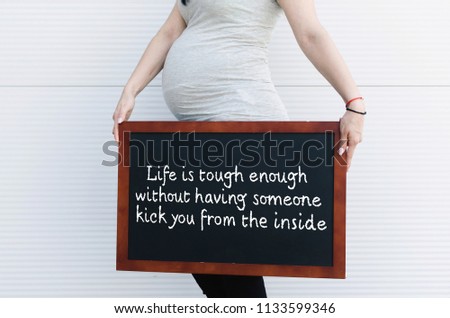 Cropped image of beautiful pregnant woman holding black board with beautiful quote.