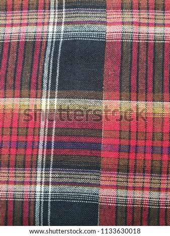 Dark colored red black and white plaid gingham fabric swatch textile background.