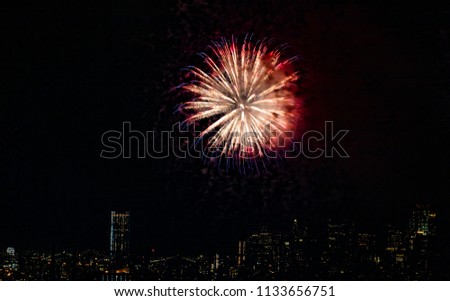 Colorful Red and White Chrysanthemum Shaped Fireworks Against Dark Sky and City Skyline  