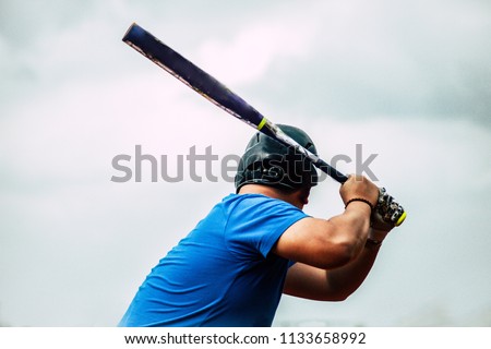 Man holding a baseball bat, ready to swing, with sky at the background