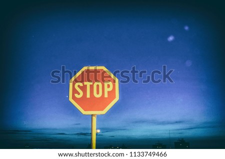 Stop sign in the night city. Traffic regulation. Blue sky. Analog photo filter with scratches.