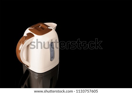Beige and brown color plastic cordless electrical kettle on the black mirror background with copy space