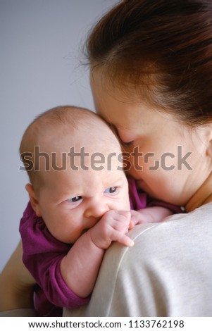 Portrait of happy young mother hugging and kissing her sweet adorable newborn child