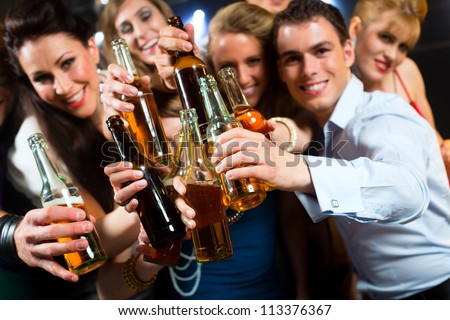 Young people in club or bar drinking beer out of a beer bottle and have fun Royalty-Free Stock Photo #113376367