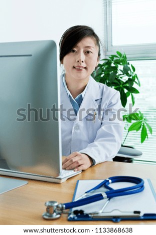 Asian woman doctor working on computer.